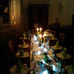 Table harmonie de vert, blanc et noir composée d'un chemin de table imitation neige avec insertion de lumière, de serviettes vertes avec initiale en cordon chenille noir et centre de table végétaux et figurines.