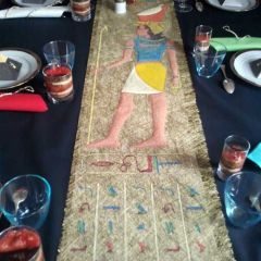 Chemin de table en tissu ajouré doré avec peinture façon hiéroglyphes et personnage égyptien au visage de la personne à l'honneur.
