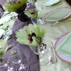 Table composée d'une nappe verte, d'un chemin de table marron , de serviettes vertes, de sacs à confiseries individuels aux mêmes harmonies de couleurs et d'un centre de table bouquet de bonbons aux tons assortis.