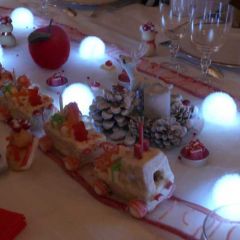 Maquette de train en gâteau recouvert de glaçage blanc, chargé de cadeaux en nougats et confiseries et posé sur un chemin de fer en bonbons.