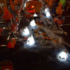 Chemin de table imitation toile d'araignée avec petites têtes de fantôme lumineuses en toile de jute.