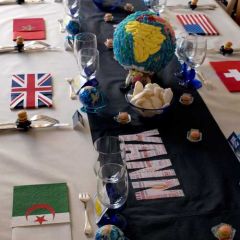 Table harmonie de noir & blanc et couleurs, composée d'une nappe blanche, d'un chemin de table noir avec inscriptions multicolores, de portes- serviette et serviettes drapeaux, aux couleurs des différents pays, de chevalets colorés.